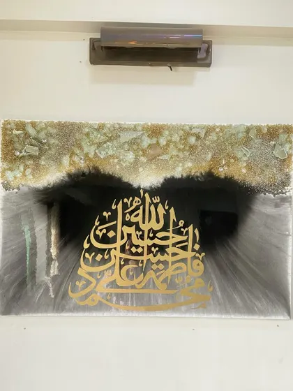 A straight-on view of the Panjatan Pak piece, highlighting the symmetry of the design and the contrast between the dark background and the golden calligraphy.