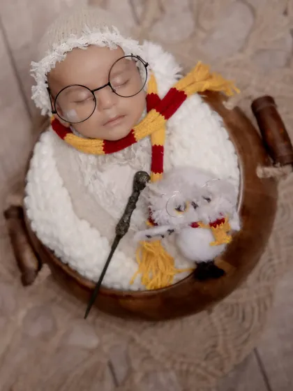 Welcome to the wizarding world, little one. This creative Harry Potter themed newborn shoot features a sleeping baby with iconic glasses, a Gryffindor scarf, and a magic wand, showing how we bring your favorite stories to life.