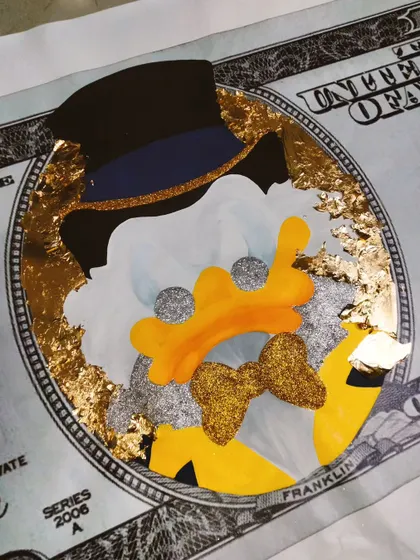 A close-up of the Scrooge McDuck canvas, showing the gold leaf details being added.