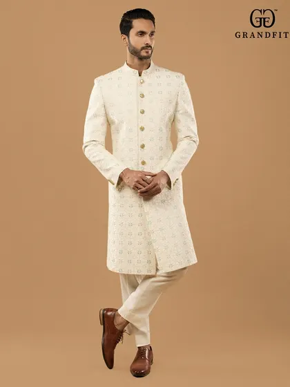 Understated elegance defined. This custom-made ivory sherwani showcases subtle, all-over embroidery on premium fabric, offering a timeless and sophisticated look for any celebration.
