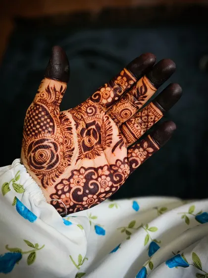 A beautiful example of a matured henna stain after a few days. The design combines floral elements with detailed filler patterns, all showing a rich, dark brown color.