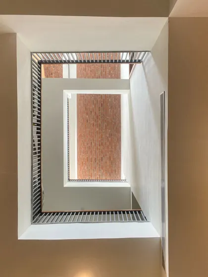 Looking straight up through the rectilinear staircase well, the design creates a powerful geometric composition of voids and solids.