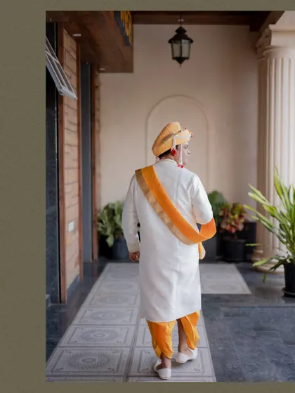 Another angle of the groom walking away, capturing the movement and elegance of his traditional outfit.