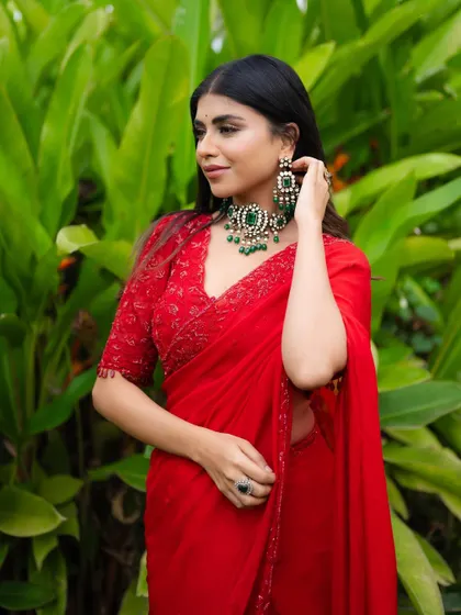 A close-up of the red organza saree, showing the detailed embroidery on the blouse and the elegant drape.