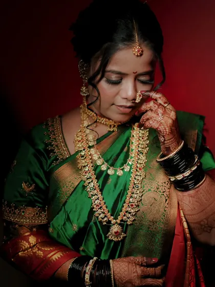 A stunning bridal portrait focusing on the rich green saree and intricate gold jewelry, a classic look for a Maharashtrian bride.