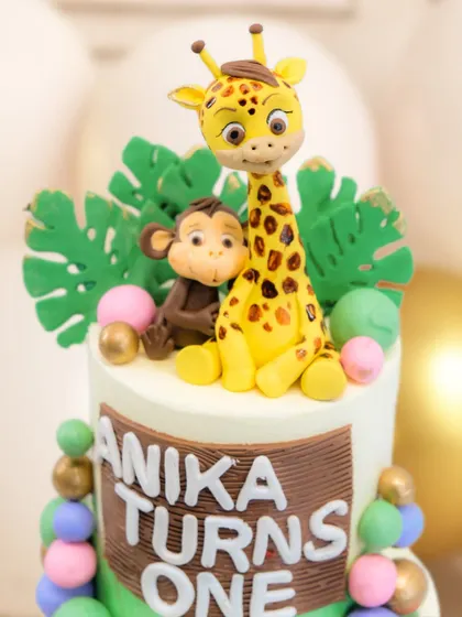 A detailed view of the giraffe and monkey toppers on the safari cake. Their playful interaction adds so much character to the design.
