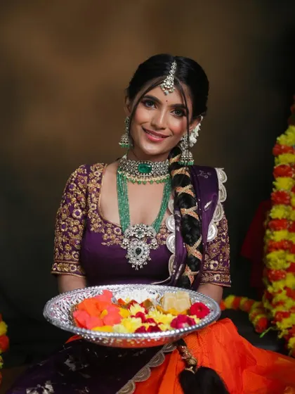 A serene portrait of the model holding a plate of flowers. The intricate details of the emerald and polki jewellery are beautifully captured in this shot.
