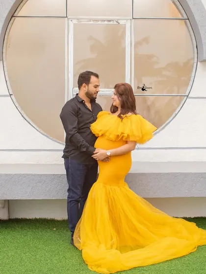 Using architectural elements like this round window adds a modern touch to the maternity shoot, even with a glamorous gown.