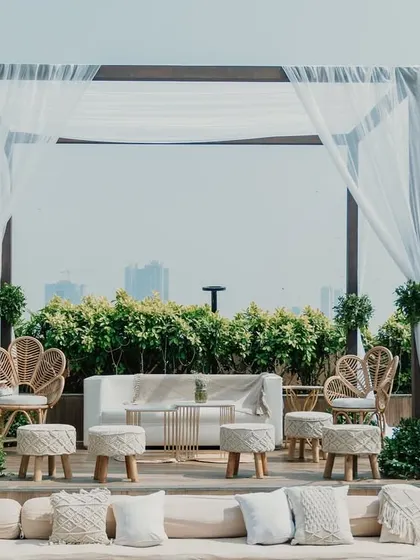 A bohemian-inspired lounge area with macrame pillows, wicker chairs, and draped fabric for a relaxed vibe.
