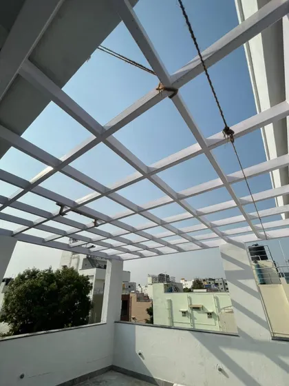A view of a white metal pergola structure on a residential terrace. This element is designed to provide partial shade and a framework for climbing plants, transforming a rooftop into a functional and beautiful garden space.