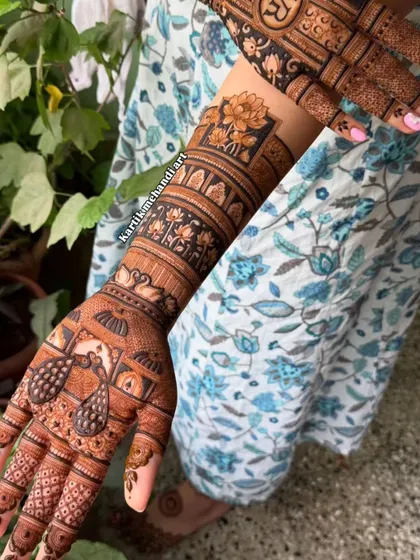 A full-arm mehandi with a prominent lotus theme. The design incorporates lotus bands, peacock figures, and intricate patterns for a complete and beautiful look.