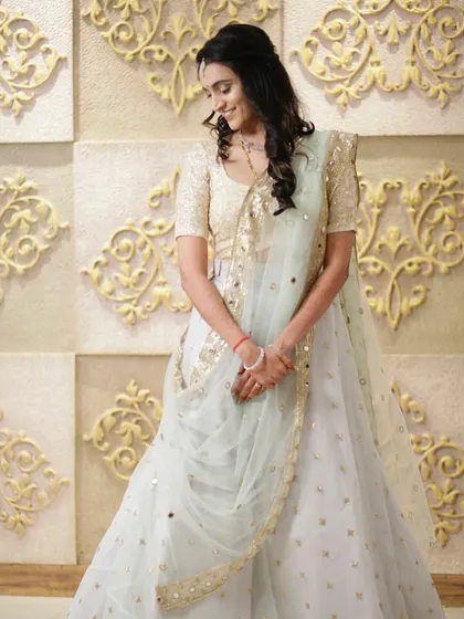 A dreamy pastel lehenga for a bride's reception. The light blue skirt is adorned with scattered gold motifs, paired with a sequined gold blouse for a touch of sparkle.