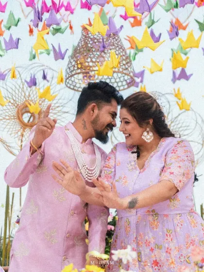 A candid moment of dance and laughter during a pre-wedding celebration. The colorful decor with paper cranes adds a whimsical touch to this shot of a couple lost in their own world of fun.