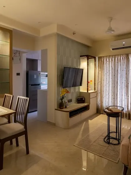 A night-time view of the living room with the fold-down dining table, showing how the space transforms with integrated lighting in the cabinetry.