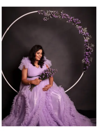 Our lavender ruffle maternity gown is perfect for a soft and dreamy photoshoot. Here it's paired with our floral ring prop for a beautiful composition.
