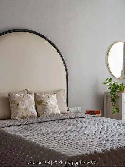 A cozy bedroom perfect for a lazy weekend in bed. The elegant arched headboard in a neutral fabric adds a touch of softness and classic charm to this restful and inviting space.