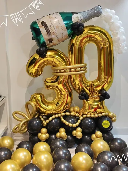 A bold and celebratory 30th birthday balloon arrangement in black and gold, featuring a champagne bottle design.
