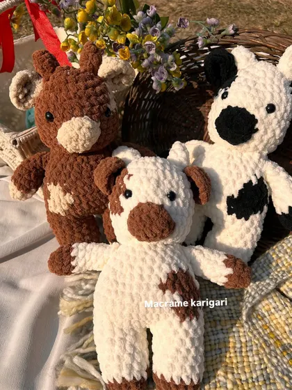 Three of our crochet cows ready for a picnic. The chunky yarn gives them a wonderfully squishy texture, perfect for little hands to hold. They are a popular choice for farm-themed nursery decor.