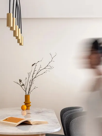 This artistic shot captures the clean aesthetic of the dining area, highlighting the form of the vase and the elegant pendant light.