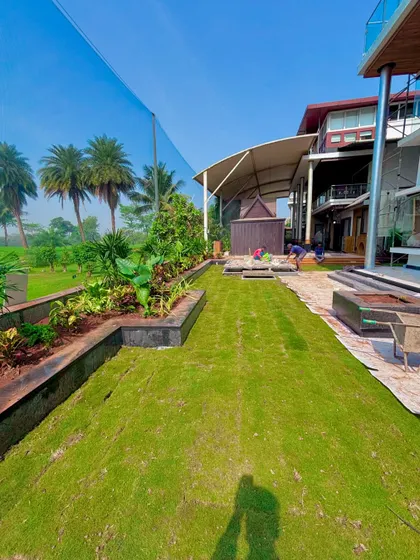 The completed lawn and garden area at the Lodha villa. This shows the final result, with the green grass connecting the house to the surrounding golf course.