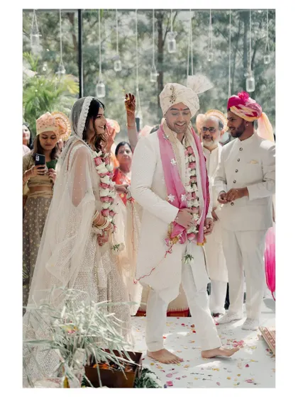 A candid shot of the couple during their pheras. The groom's happy expression and the guests in the background create a lively and joyful ceremony photograph.