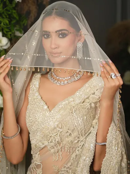 A vision in white. This portrait showcases a delicate, fully embroidered saree by Nitika Gujral. The sheer, veiled look adds a layer of mystique and romance, perfect for a Christian wedding or reception.