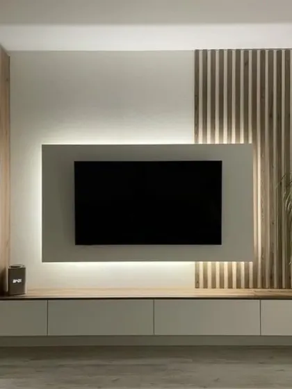 This design balances different materials and textures, combining a smooth white panel with backlighting for the TV mount, warm wood shelving, and vertical wood slats. The result is a modern and visually interesting media center.