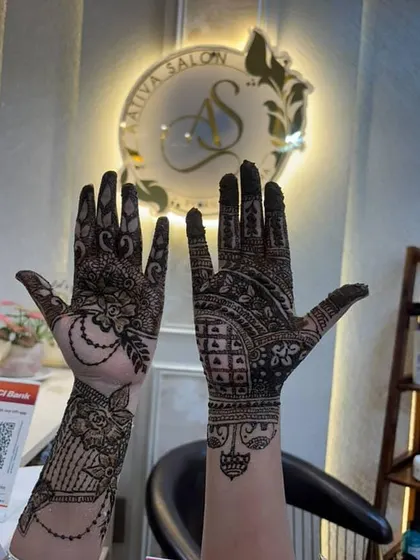 This image showcases two distinct and detailed mehendi styles applied at my salon. On the left, you can see a traditional design with floral and paisley motifs on the palm and wrist, while the right hand features a more geometric pattern combined with classic elements, covering the entire palm and fingers.
