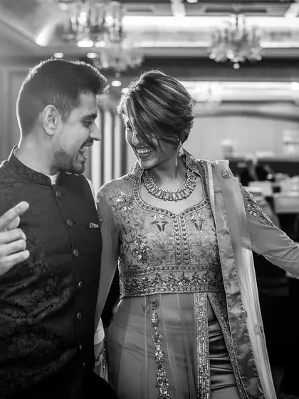 A candid black and white shot of a couple dancing. The backlighting and their happy expressions create a beautiful, atmospheric party photo.