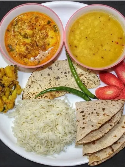 A complete, colorful meal on a single plate. This thali has everything: rice, rotis, dal, a creamy curry, a dry sabzi, papad, and even fresh strawberries for a touch of sweetness.