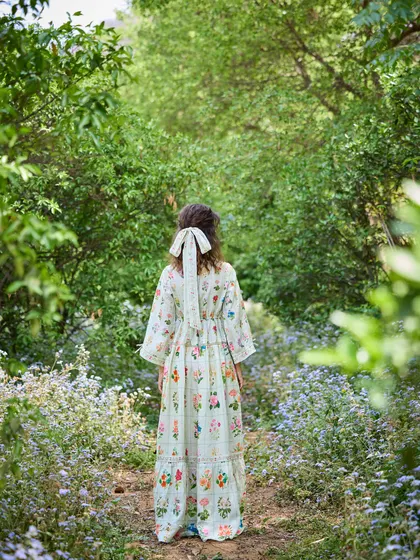 A back view of the same dress, highlighting the bow detail in the hair and the way the model blends into the natural surroundings. This shot is all about creating a mood and a story.