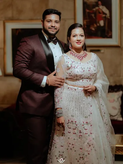 A classic, formal engagement portrait of a couple in an elegantly decorated room.