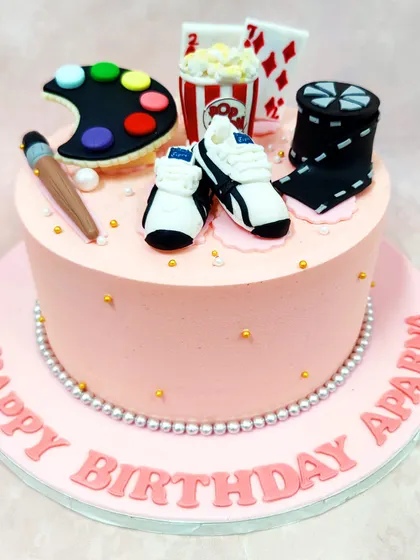 We create a cake that celebrates a multitude of passions with this unique hobby theme cake. Featuring an artist's palette, playing cards, popcorn, and running shoes, this cake is a personalized tribute to someone's favorite things.