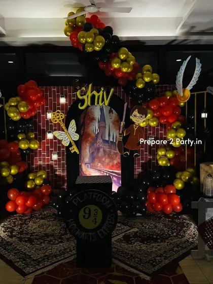 A full view of an immersive Harry Potter themed birthday party. The setup includes a brick wall backdrop, a Hogwarts entrance, character cutouts, and balloon decorations in Gryffindor colors.