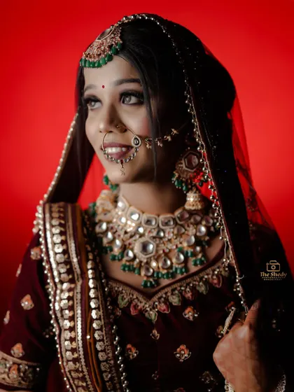 A happy and radiant bridal portrait. The bright red background makes the bride's smile and beautiful jewelry pop.