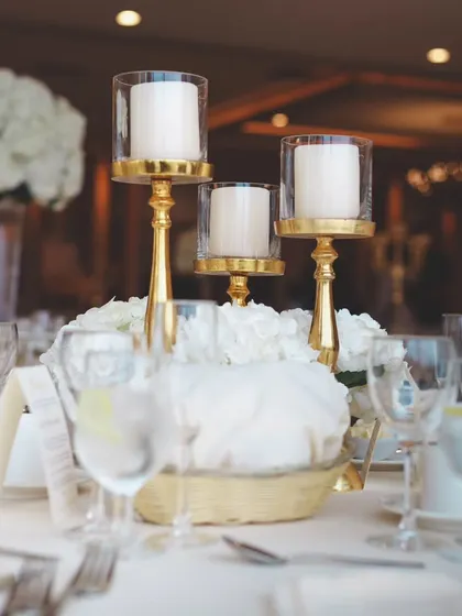 A classic and elegant table setting with white roses and gold candle holders. This timeless combination exudes sophistication and romance, perfect for a formal wedding reception.