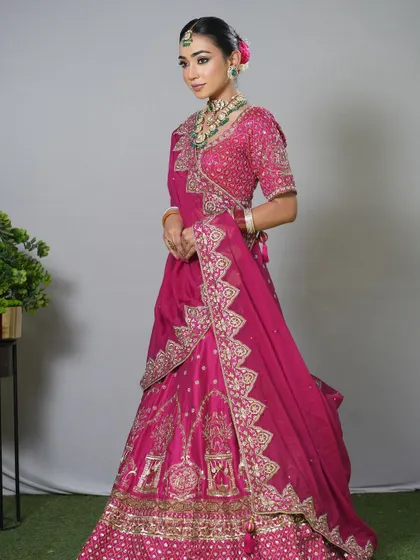 A full-length shot of a bride in a pink lehenga, her hair in a classic floral bun.