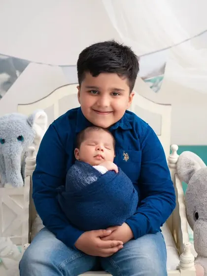 A big brother's proud embrace. We created a dreamy, cloud-like setting with soft blue tones and plush elephants to capture this sweet moment between two brothers.