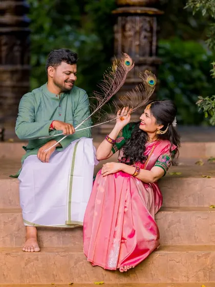 A playful moment with peacock feathers on a stone staircase. This candid shot captures the couple's fun-loving personalities in a beautiful, natural setting.