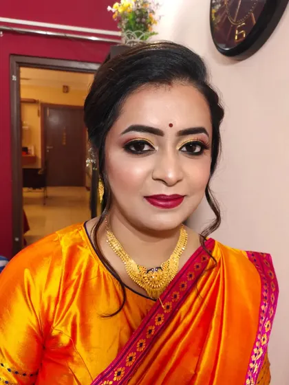 A portrait of the client, looking elegant and ready for her event in a bright orange and pink saree.