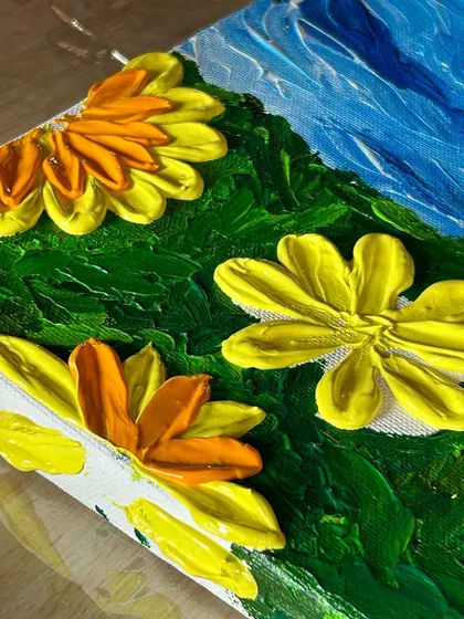 A detailed shot of the thick, textured petals of a sunflower created with a palette knife, showcasing the impasto technique taught in our workshops.