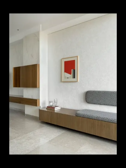 Clean lines and honest materials define this entryway. A long, floating wooden bench with integrated seating provides a functional and minimalist welcome. The space is kept deliberately simple, allowing the textures of the wall finish and a single piece of art to make a quiet statement.