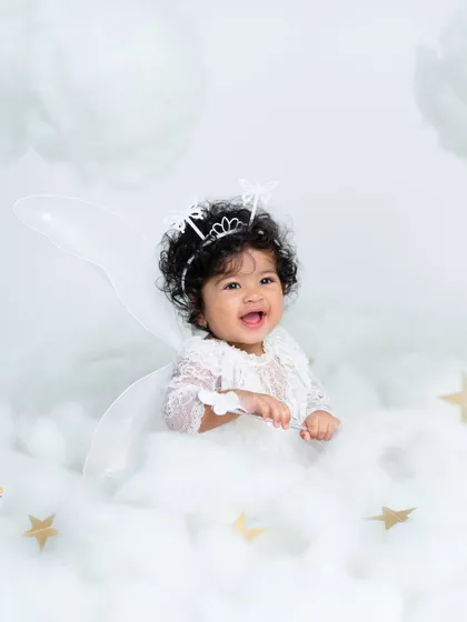 A happy angel with the sweetest smile. The all-white theme with fairy wings and a butterfly crown creates a truly heavenly and magical portrait.
