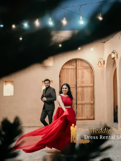 A night shoot with a couple in a red crop top set and a black suit. The flowing fabric of the skirt adds a touch of drama to this romantic evening scene.