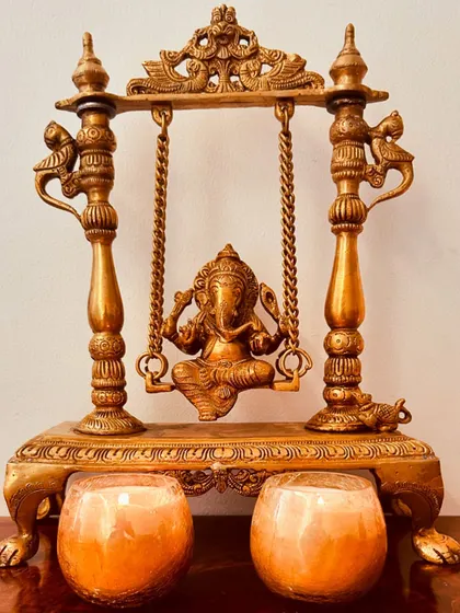 A set of two beautiful scented candles in cracked glass jars, placed in front of a Ganesha idol. They are perfect for lighting up your home during Diwali.