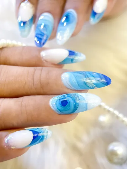 A stunning blue and white mosaic nail art design. This style uses blooming gel to create mesmerizing, layered patterns that resemble natural stone.