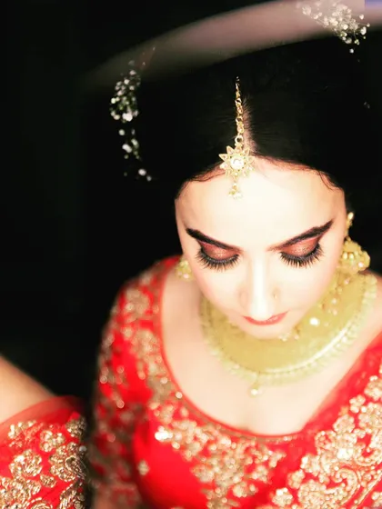 A classic bridal portrait, with the bride looking down. This angle highlights her beautiful eye makeup and the intricate details of her maang tikka.