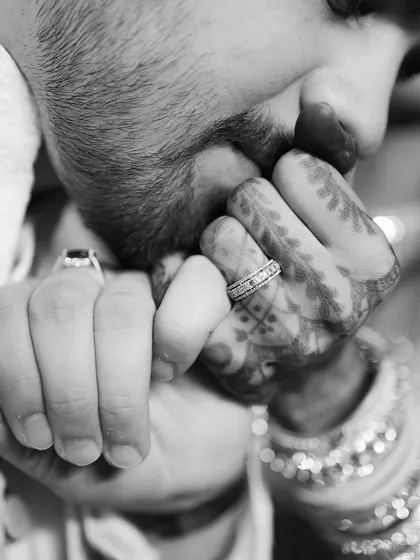 A tender and classic black and white shot focusing on the details of an engagement. The groom kissing his fiancée's hand, adorned with henna and the engagement ring, is a timeless expression of love and respect.