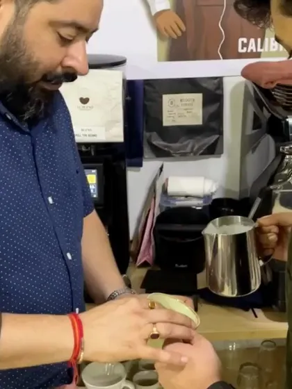 A trainer providing personalized instruction on milk pouring. This individual attention is key to mastering the art and science of coffee making.