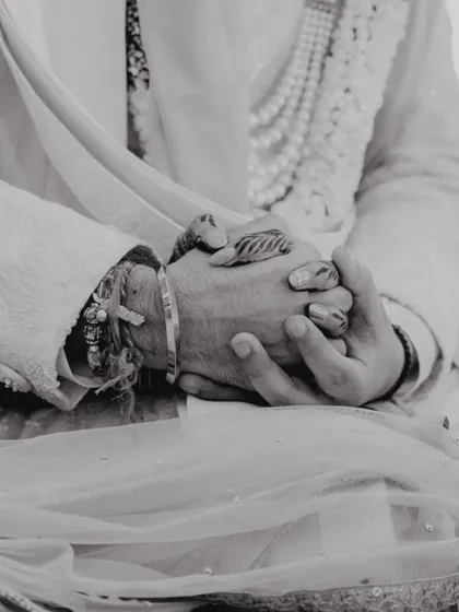 A black and white close-up of the couple's hands clasped together during the ceremony, a symbol of their union.